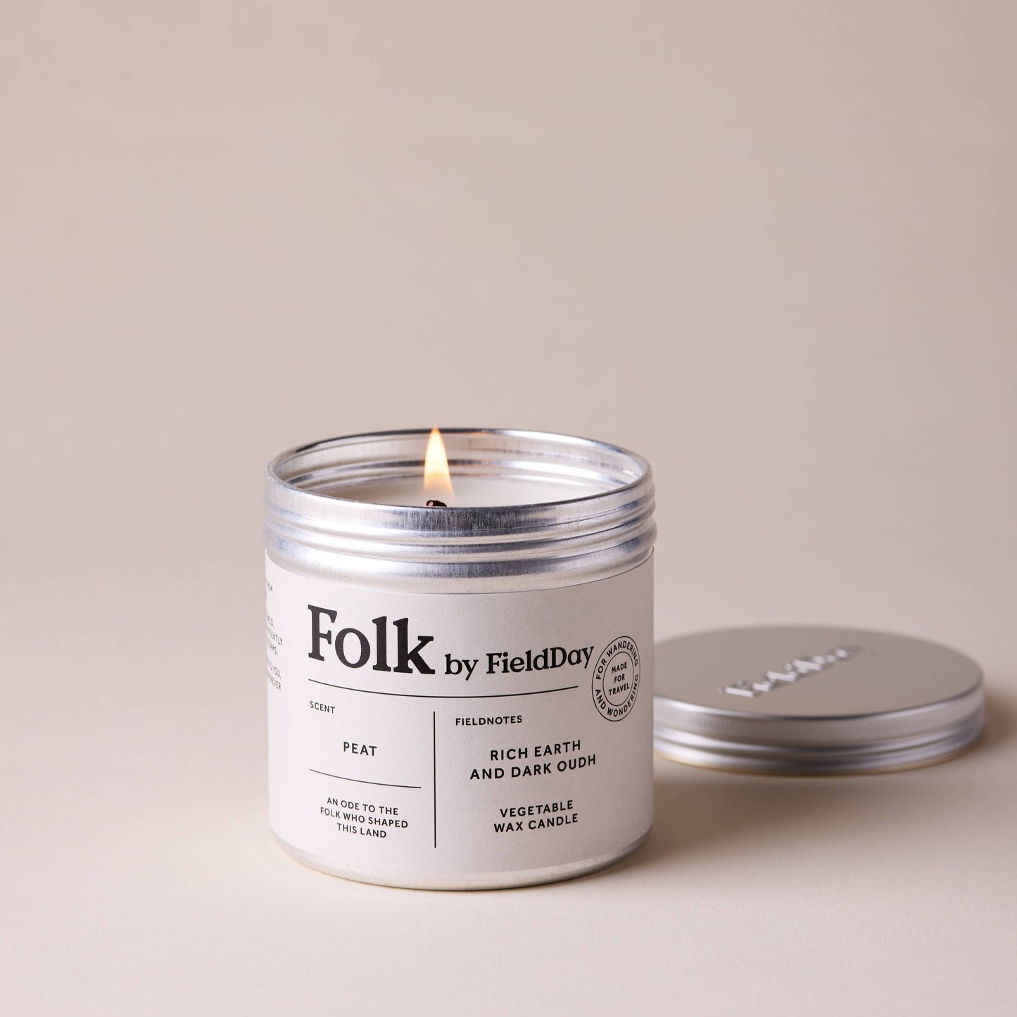 Candle labeled 'Folk by Field Day' with a lit wick on a beige background