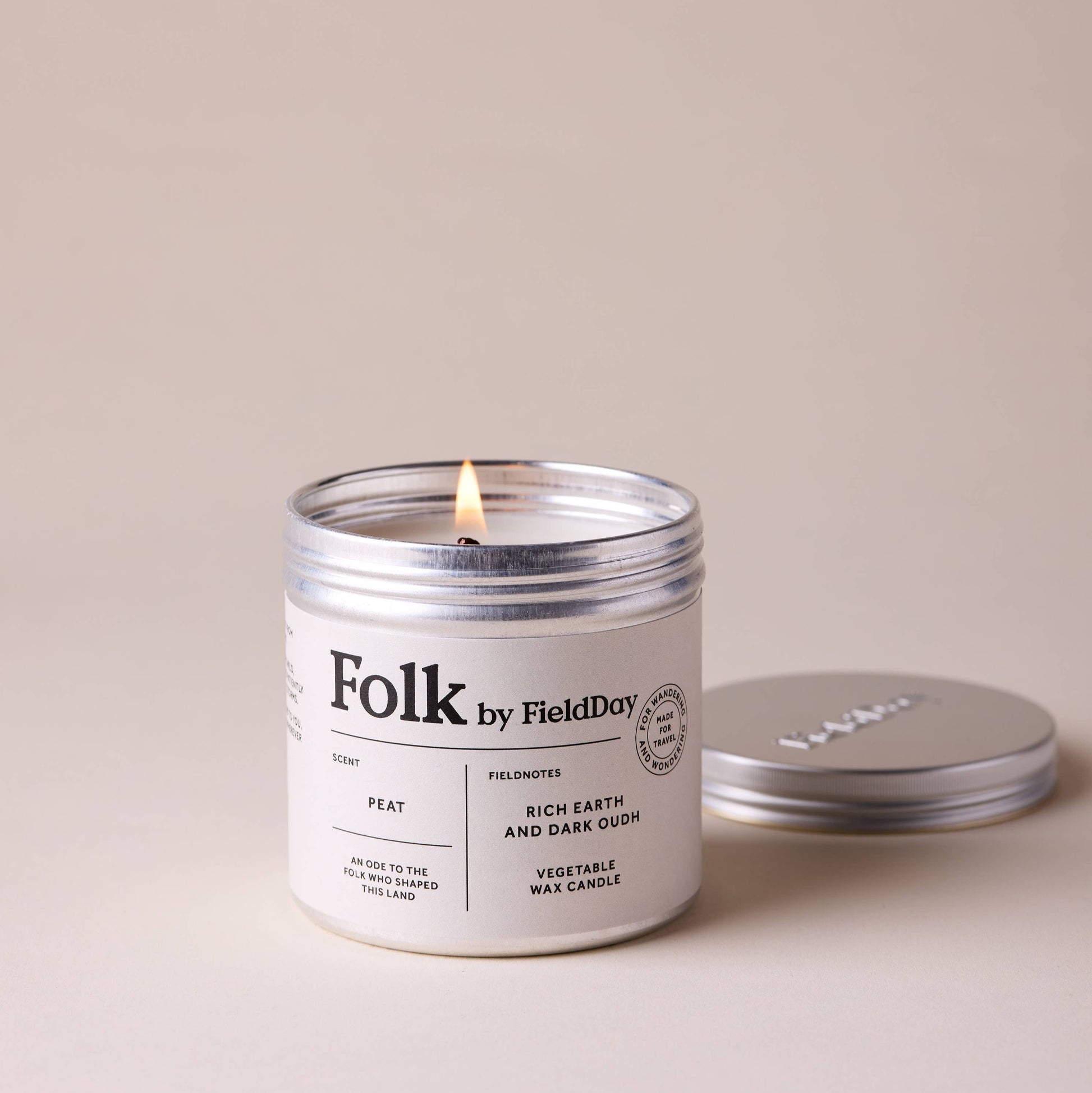 Candle labeled 'Folk by Field Day' with a lit wick on a beige background