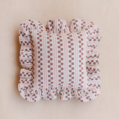 Pink Checkered  and striped cushion with ruffled trim on a beige background