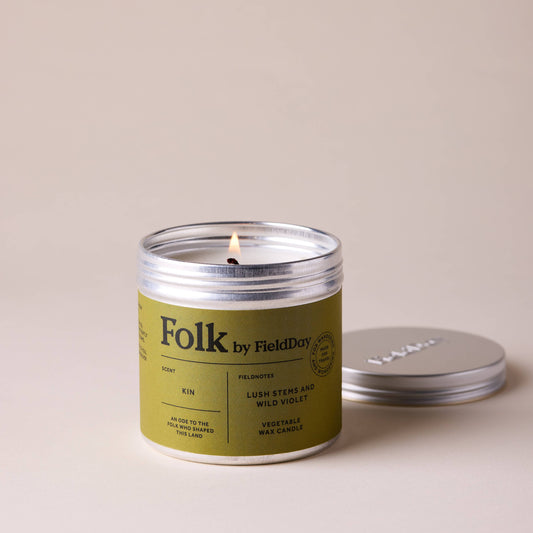 Candle with a green label and silver lid on a beige background